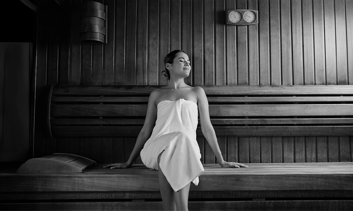 Woman relaxing in a traditional wooden sauna during a contrast therapy Dubai session at Pure Heat Club.