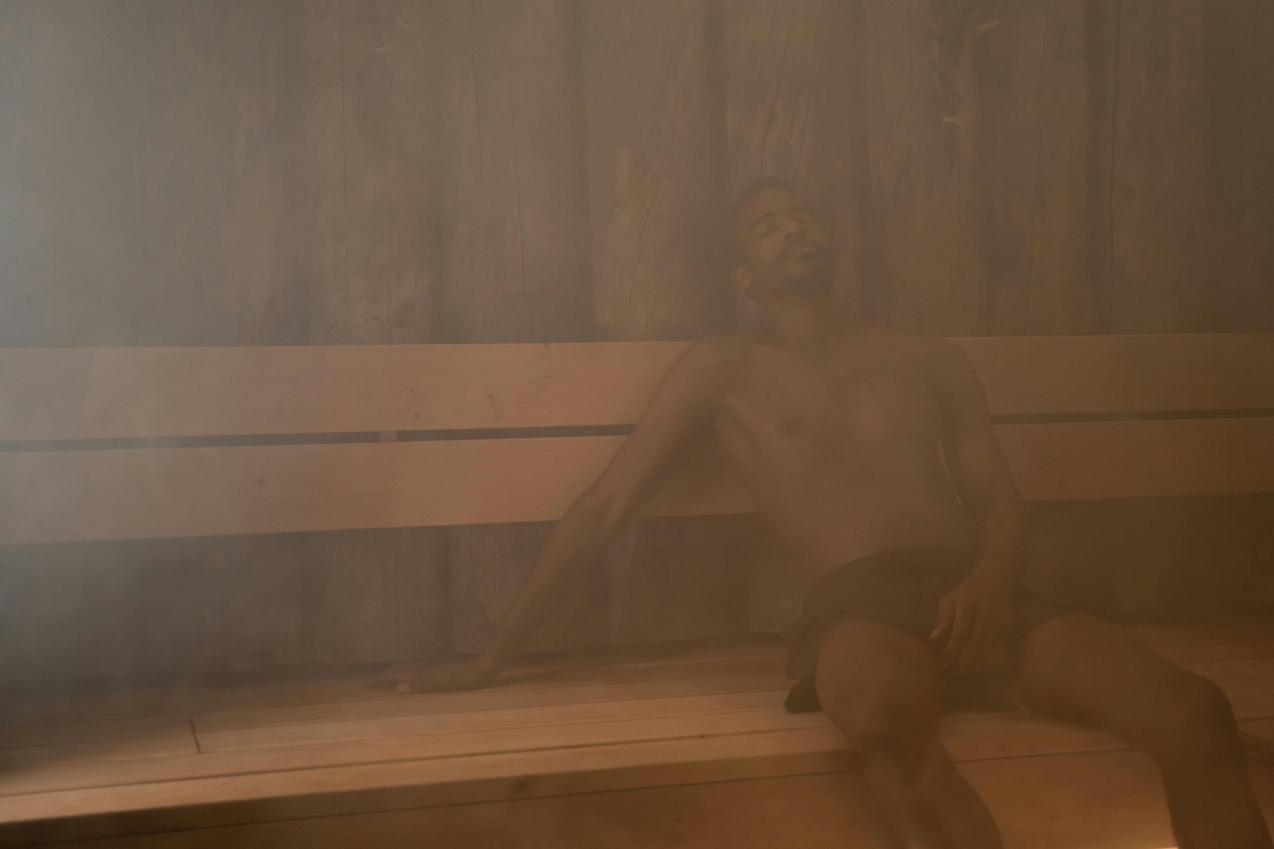 Person relaxing in a steam-filled sauna during a heat exposure session