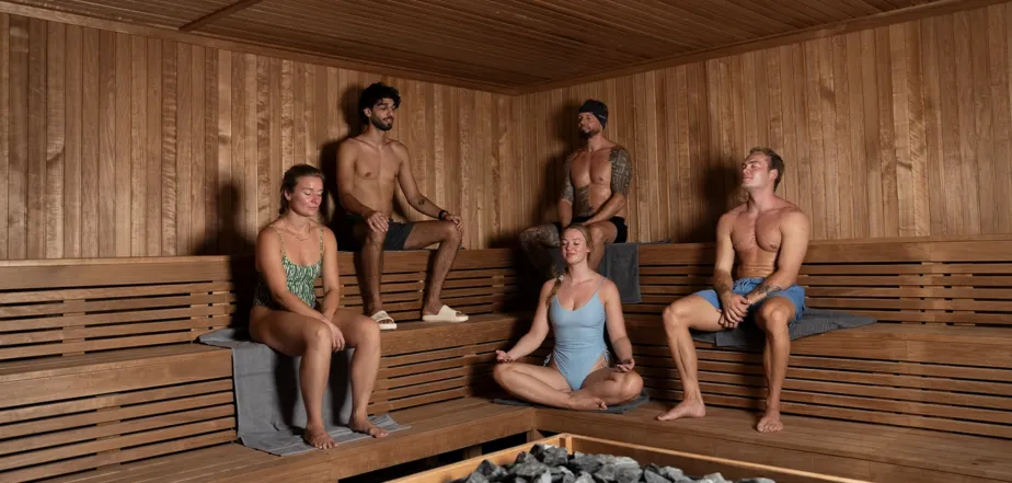 Diverse group of members sharing a collective wellness session inside the sauna.